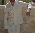 Sher Valor Sandstone Set – men's beige linen shirt close-up, relaxed open collar and button detail against stone wall
