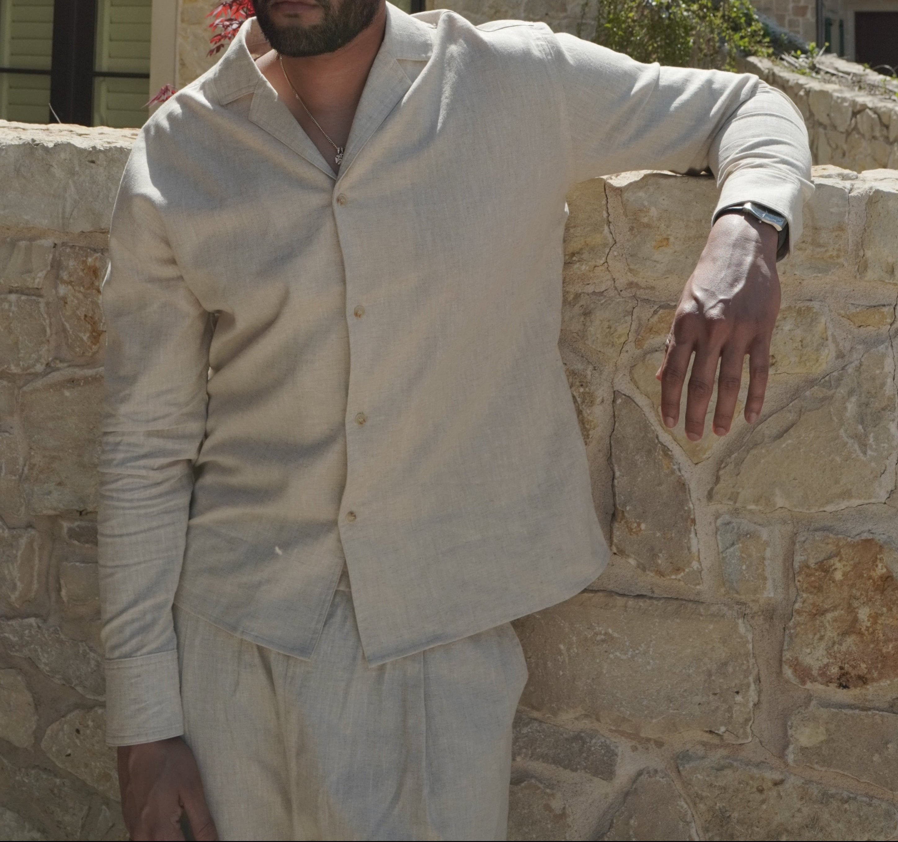 Sher Valor Sandstone Set – men's beige linen shirt close-up, relaxed open collar and button detail against stone wall